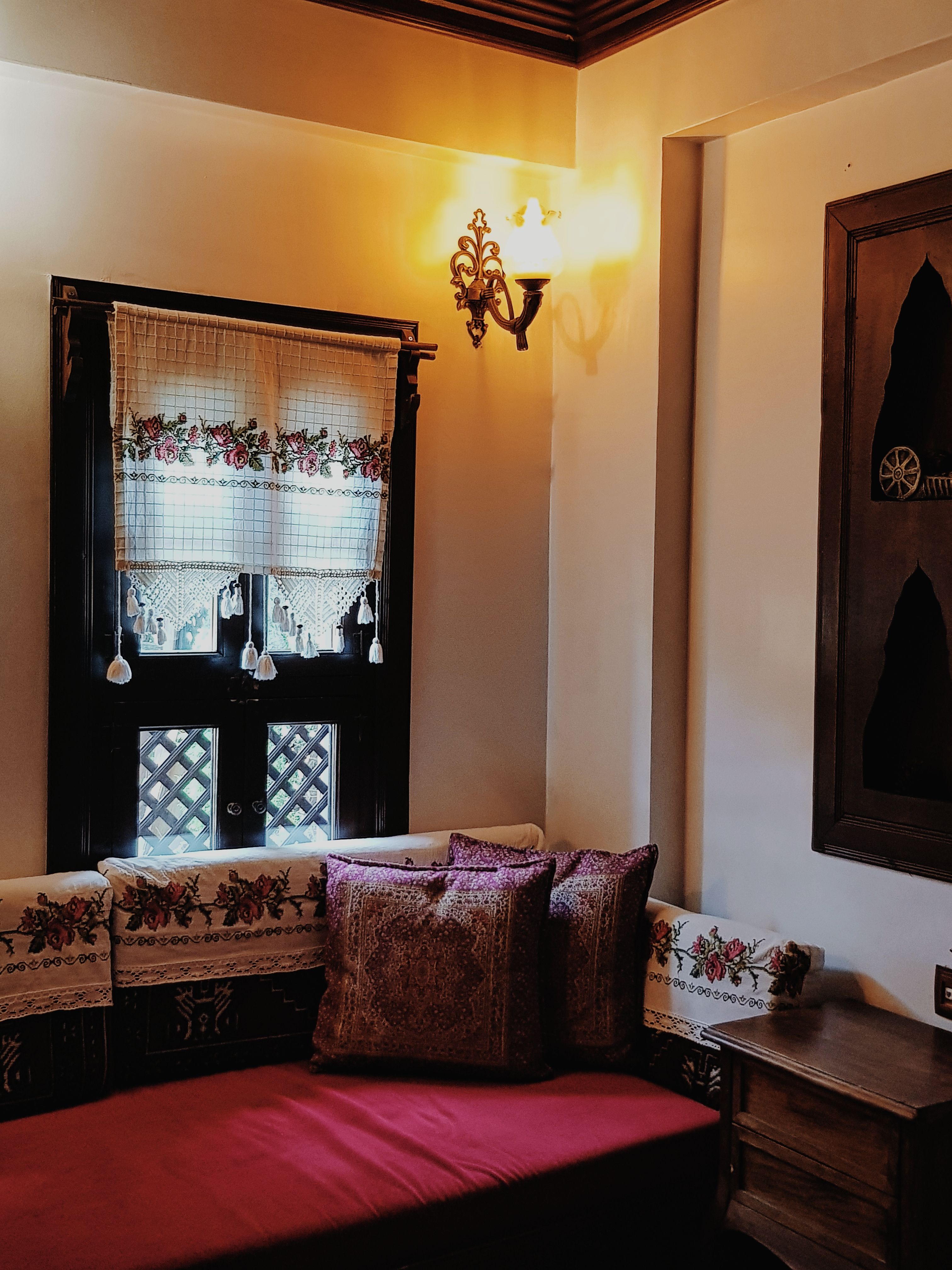 Warm cozy corner in a vintage room featuring wooden window, floral drapes, and plush seating.