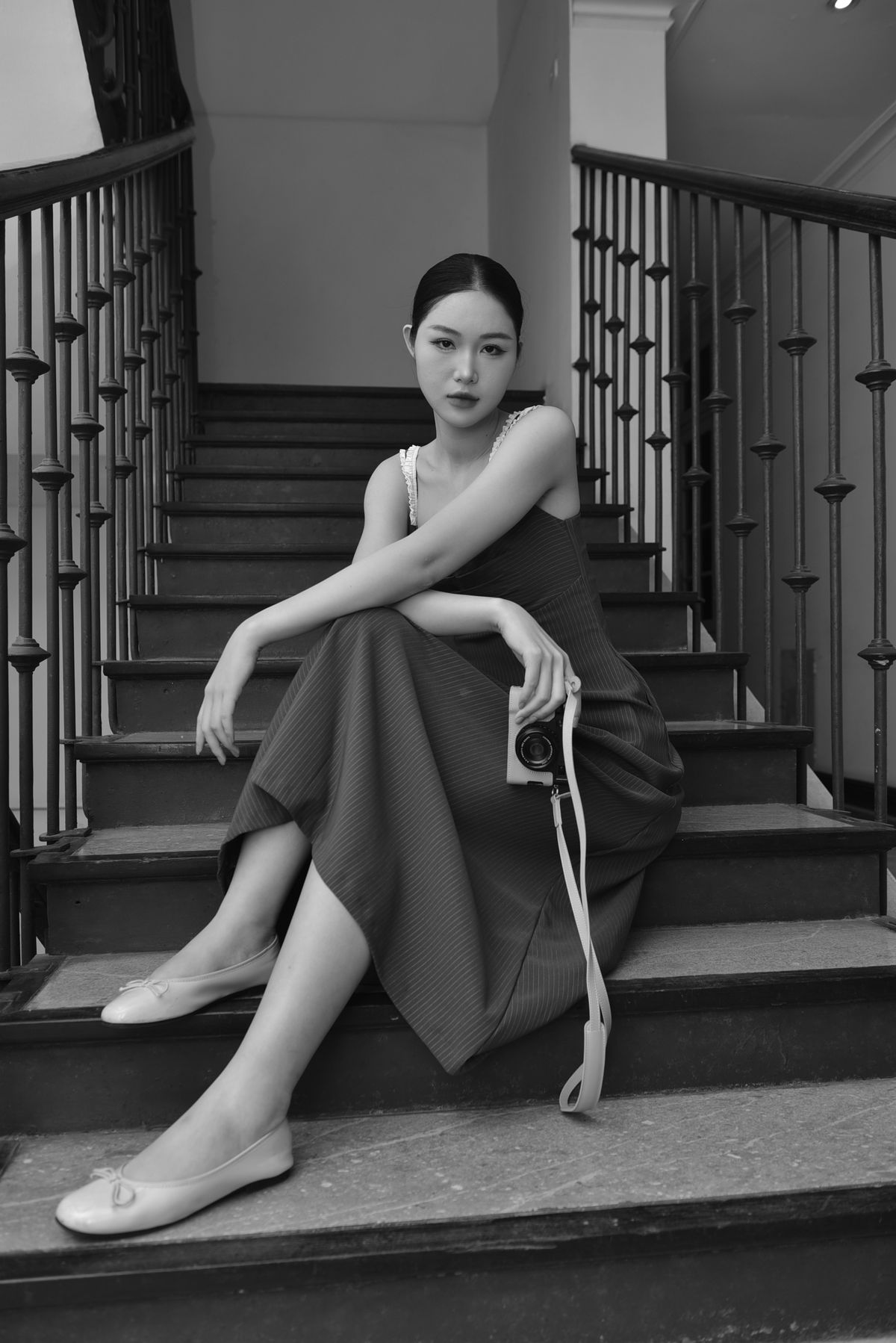 An elegant woman posed on a staircase in ballet flats, black and white — styling the flat