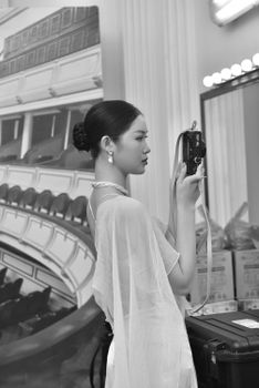 Black and white portrait of a woman photographing backstage.