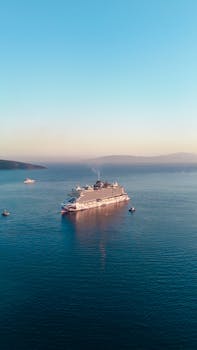 A luxury cruise ship sails serenely on open water during a vibrant sunset.