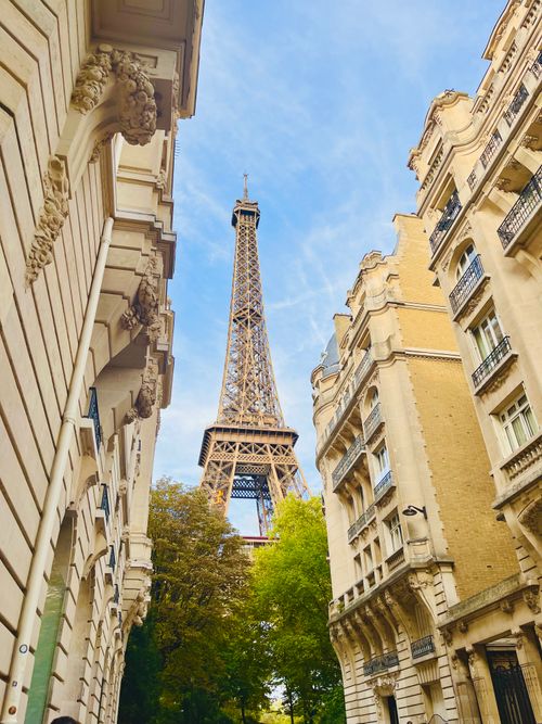 Free Charming view of the Eiffel Tower framed by classic Paris architecture under a bright blue sky. Stock Photo