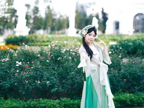 Woman in traditional attire poses gracefully in a vibrant garden.