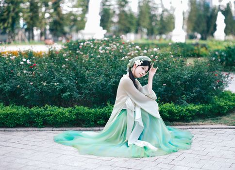 Woman in traditional dress kneeling in a beautiful garden. Captured with a soft and vibrant tone.