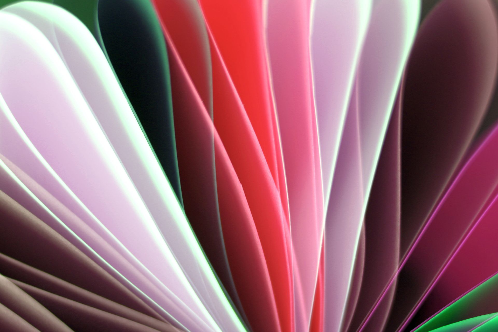 Vibrant abstract photo of multicolored paper folds in a spectrum of pink, red, and green hues.