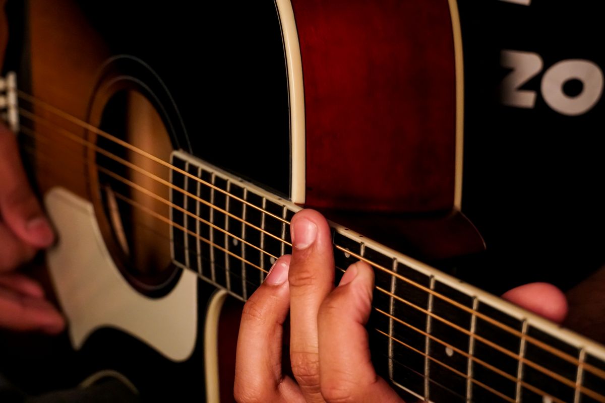 Close-up of fingers on acoustic guitar strings