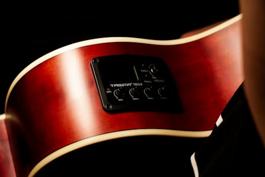 Detailed view of a red acoustic guitar's body with visible volume and tone controls.