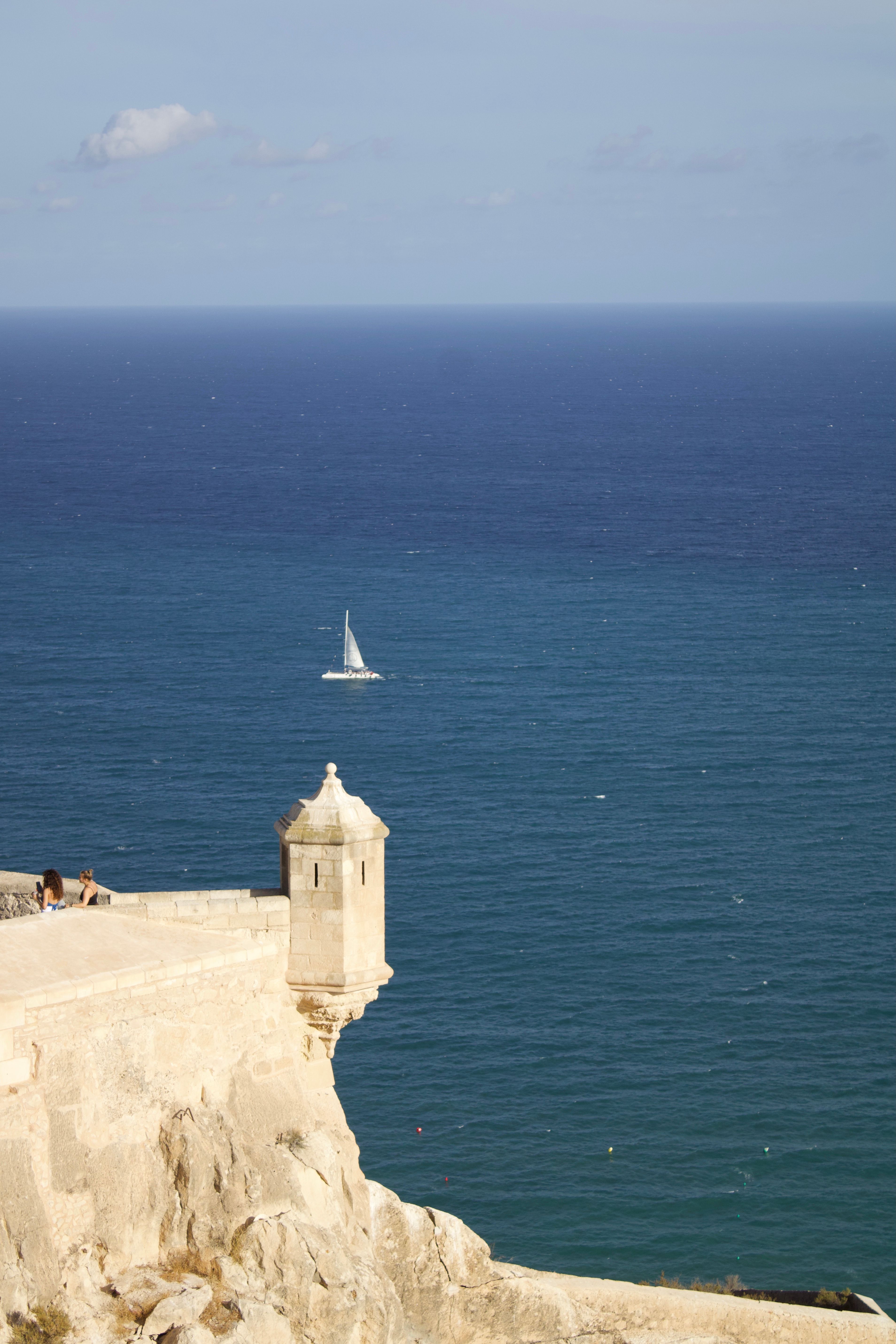 Scenic view of the Mediterranean Sea from Santa Barbara Castle in Alicante with a sailboat in the distance.