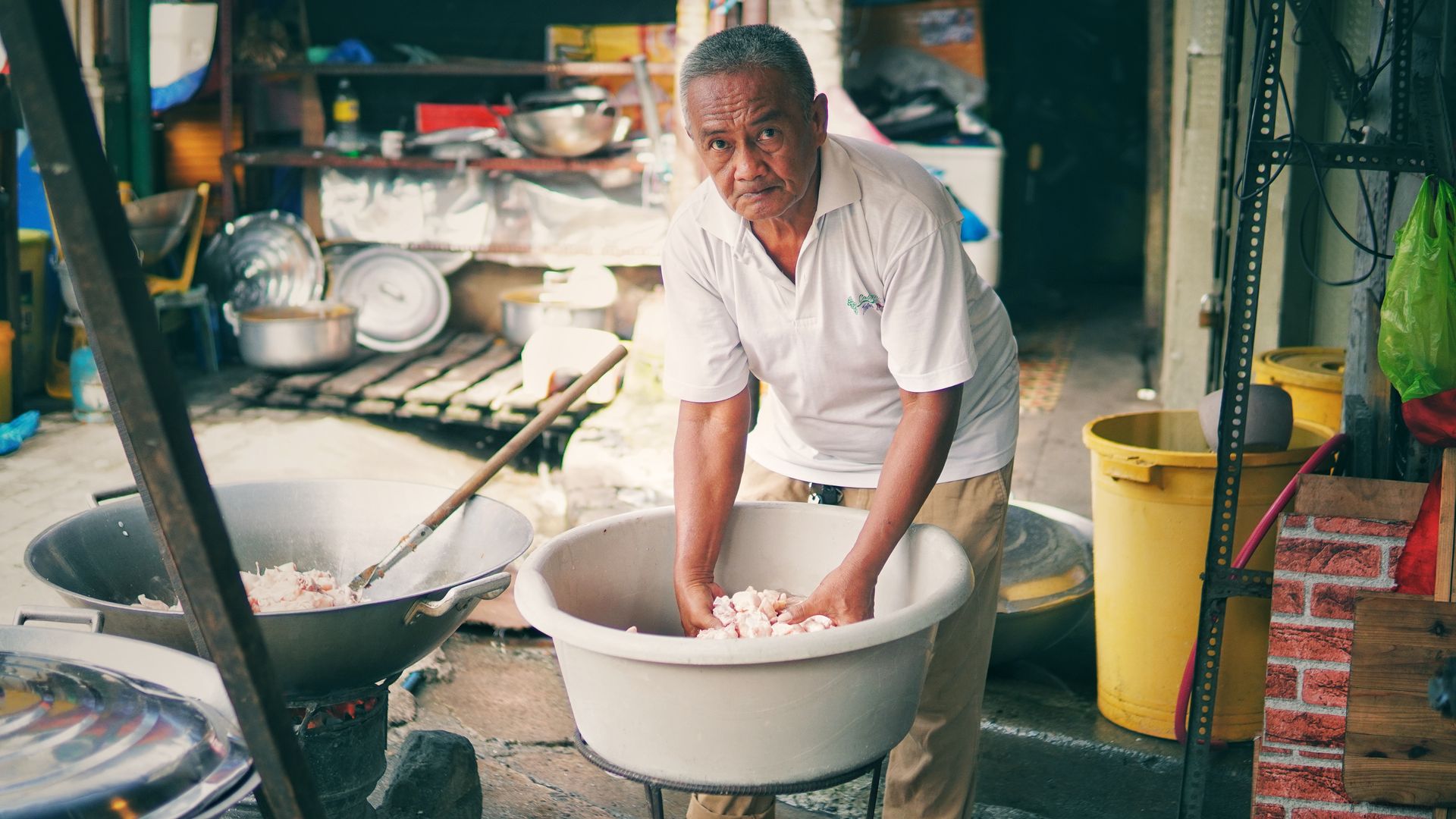 Senior man working with ingredients in an outdoor kitchen setup.