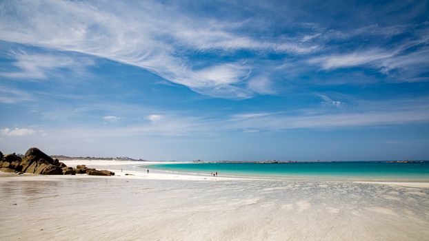 Serene beach scene at Bretagne, France with clear skies and azure waters.