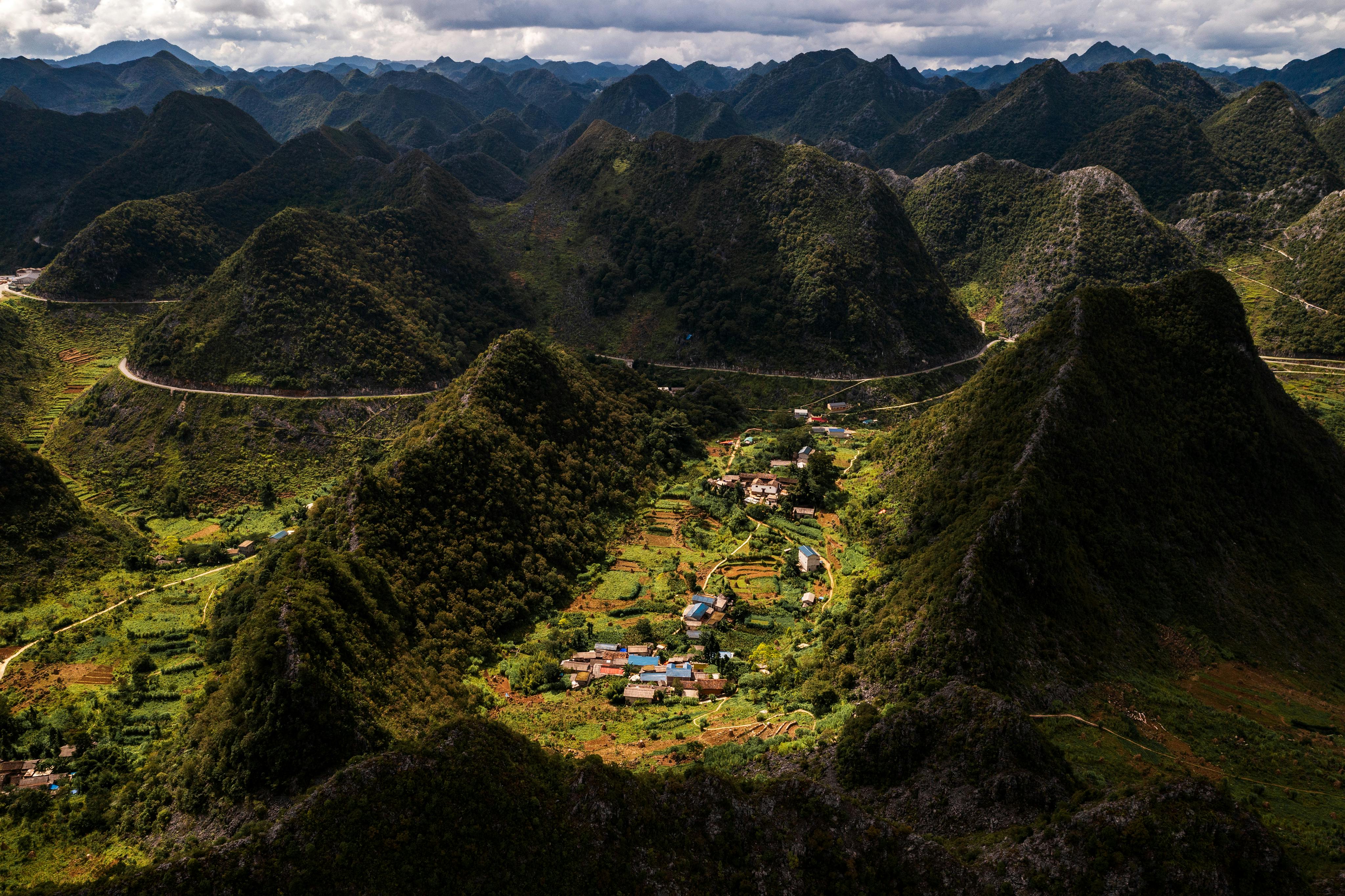 бесплатная Живописный вид с воздуха на оживленную деревню, расположенную в пышной зеленой горной долине. Стоковое фото