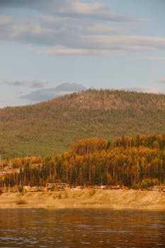 Beautiful autumn landscape featuring forested mountains and a serene river in Irkutsk, Russia.
