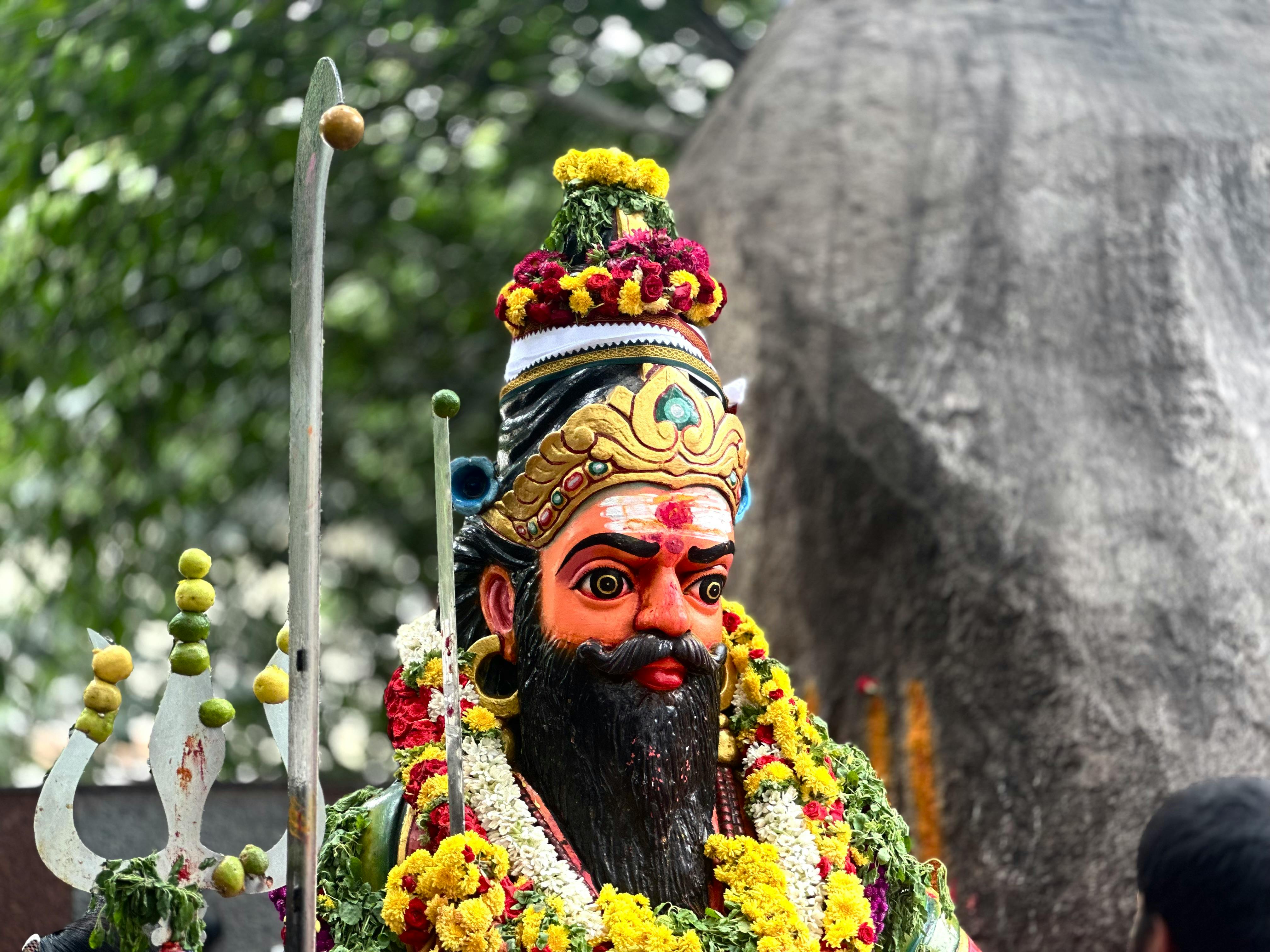 Vibrant Hindu god statue adorned with flowers outdoors in Bengaluru, India.