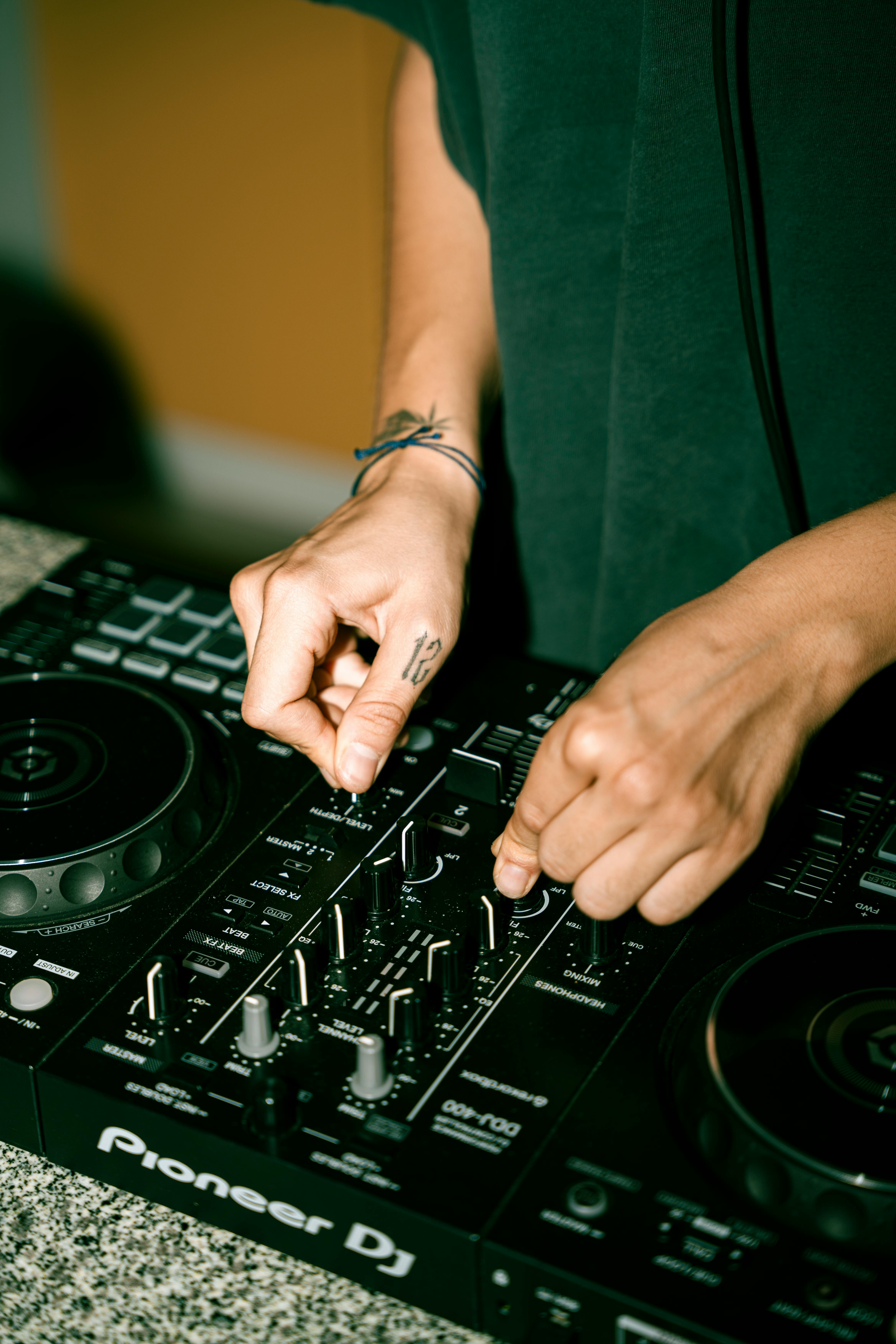 Close-up of hands adjusting settings on a Pioneer DJ mixer.