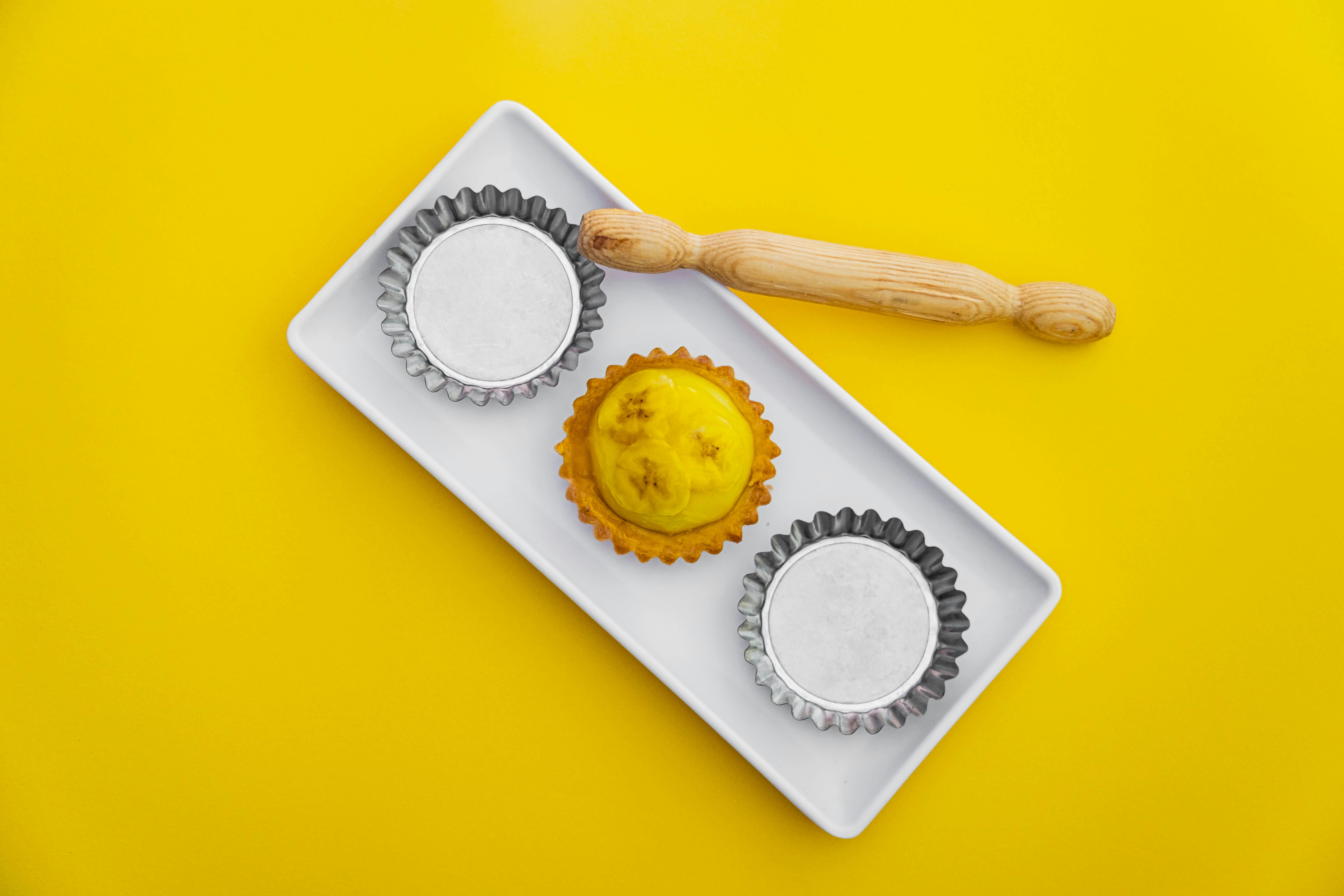 Flat lay of an artisanal yellow tart and bakeware on a vibrant yellow backdrop.
