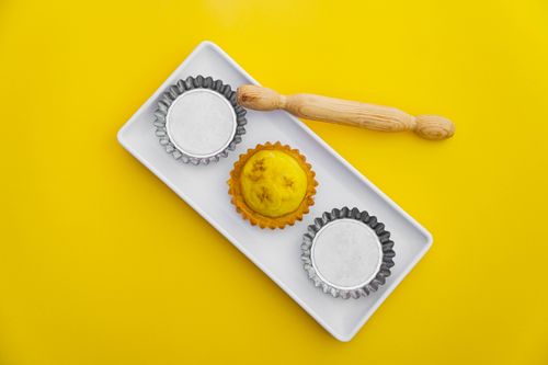 Free Flat lay of an artisanal yellow tart and bakeware on a vibrant yellow backdrop. Stock Photo