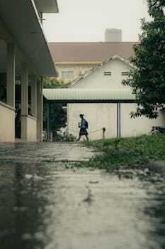 A person walks casually through a rainy university campus in Phnom Penh, Cambodia.