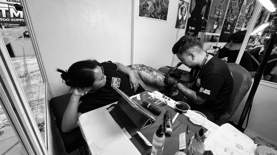 Tattoo artist ink woman in casual tattoo studio setting. Tattoo artist ink woman in casual tattoo studio setting.