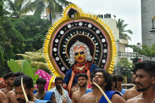 Men in traditional attire celebrate a cultural festival parade in Karnataka with vibrant costumes and ceremonial accessories.