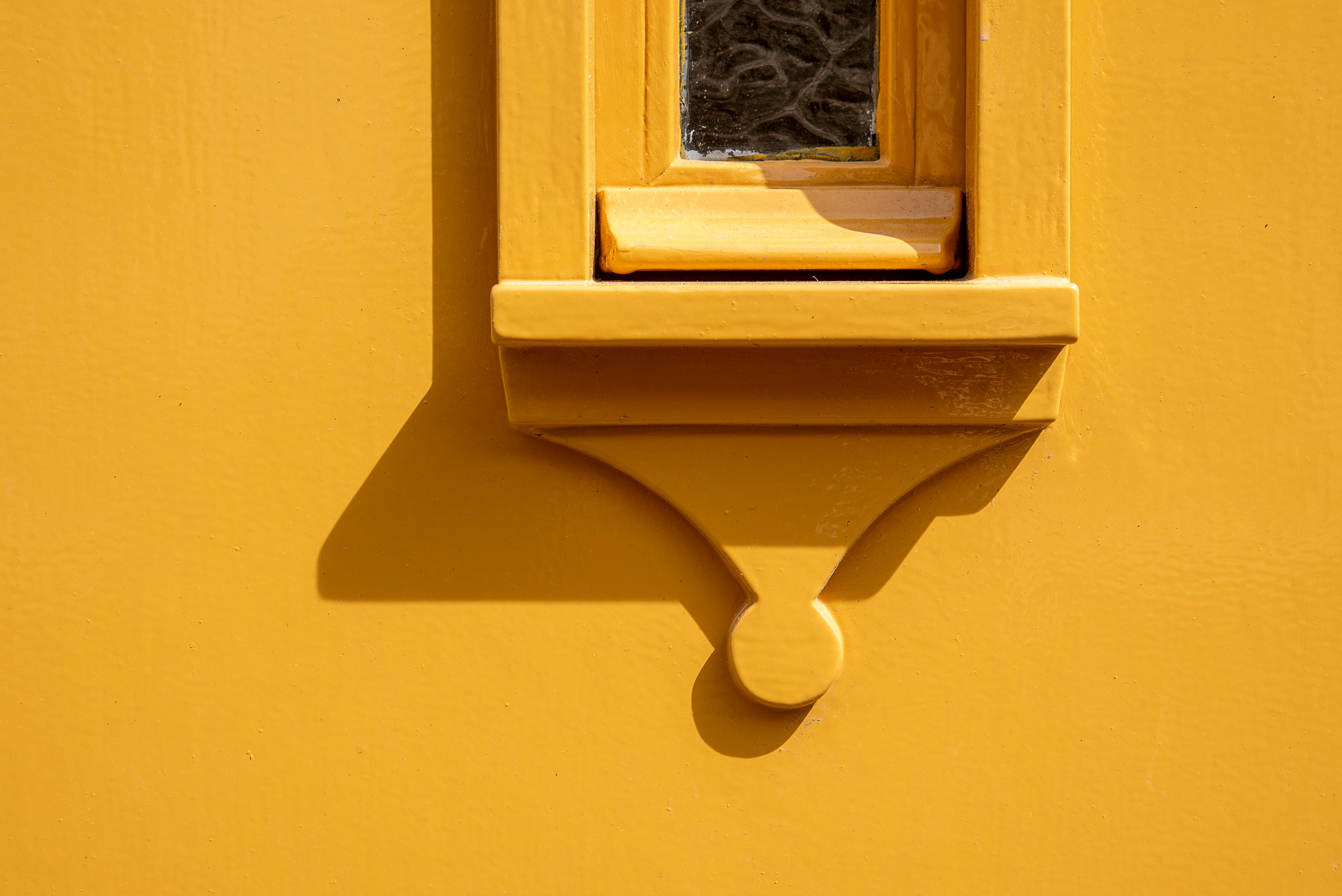 免費 特寫：一面紋理鮮明的牆上有一個黃色的小窗戶，形成一副光影戲。 圖庫相片