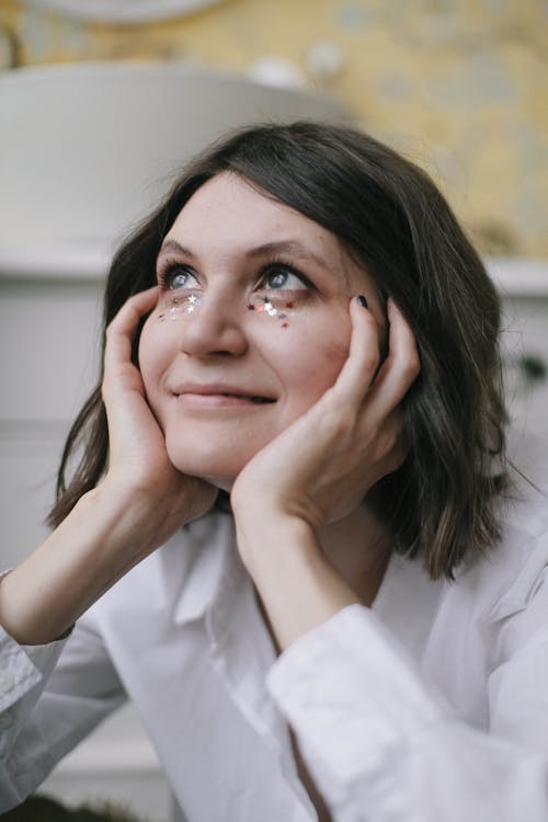 Free Woman in White Long-sleeved Top Holding Her Face Stock Photo