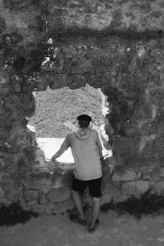 A person gazing through a stone window in an ancient ruin, creating a nostalgic feel.