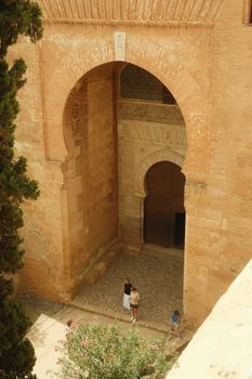 Aerial view showcasing the intricate architecture of Alhambra's entrance with visitors below.