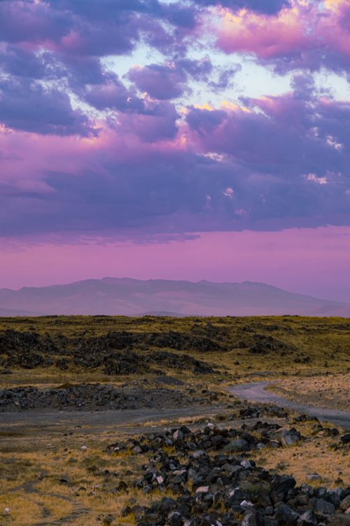 Free Vibrant sunset with purple skies over a desolate desert landscape. Stock Photo