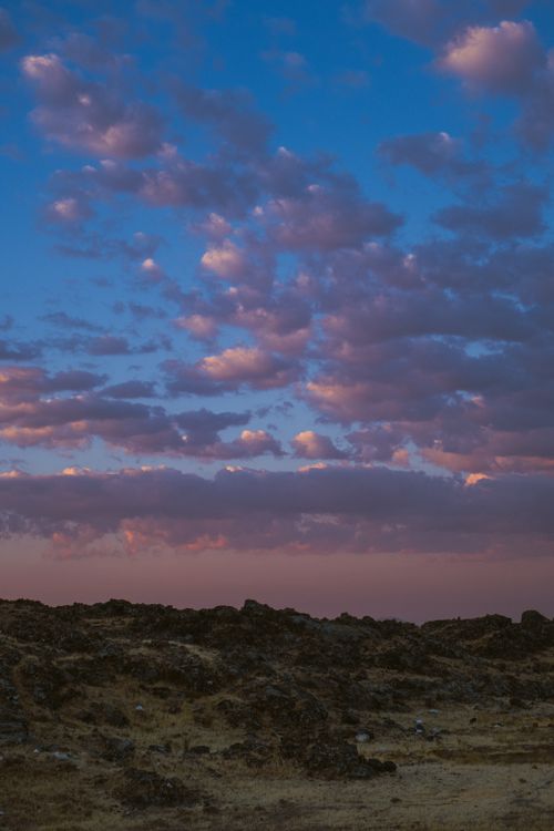 Free Stunning sunset with vibrant clouds over a rocky terrain. Stock Photo
