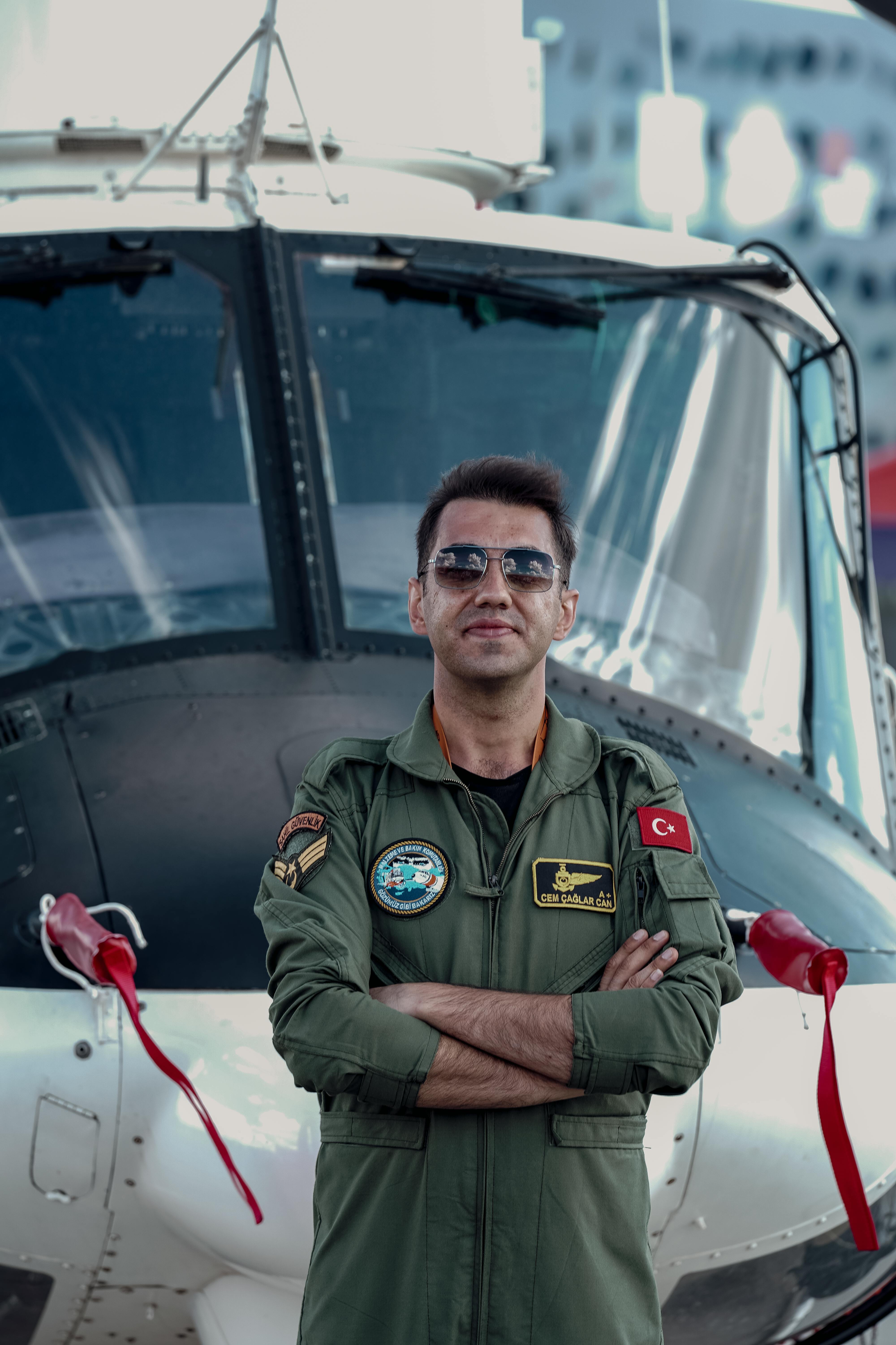 Confident pilot posing in front of a helicopter wearing Turkish uniform.