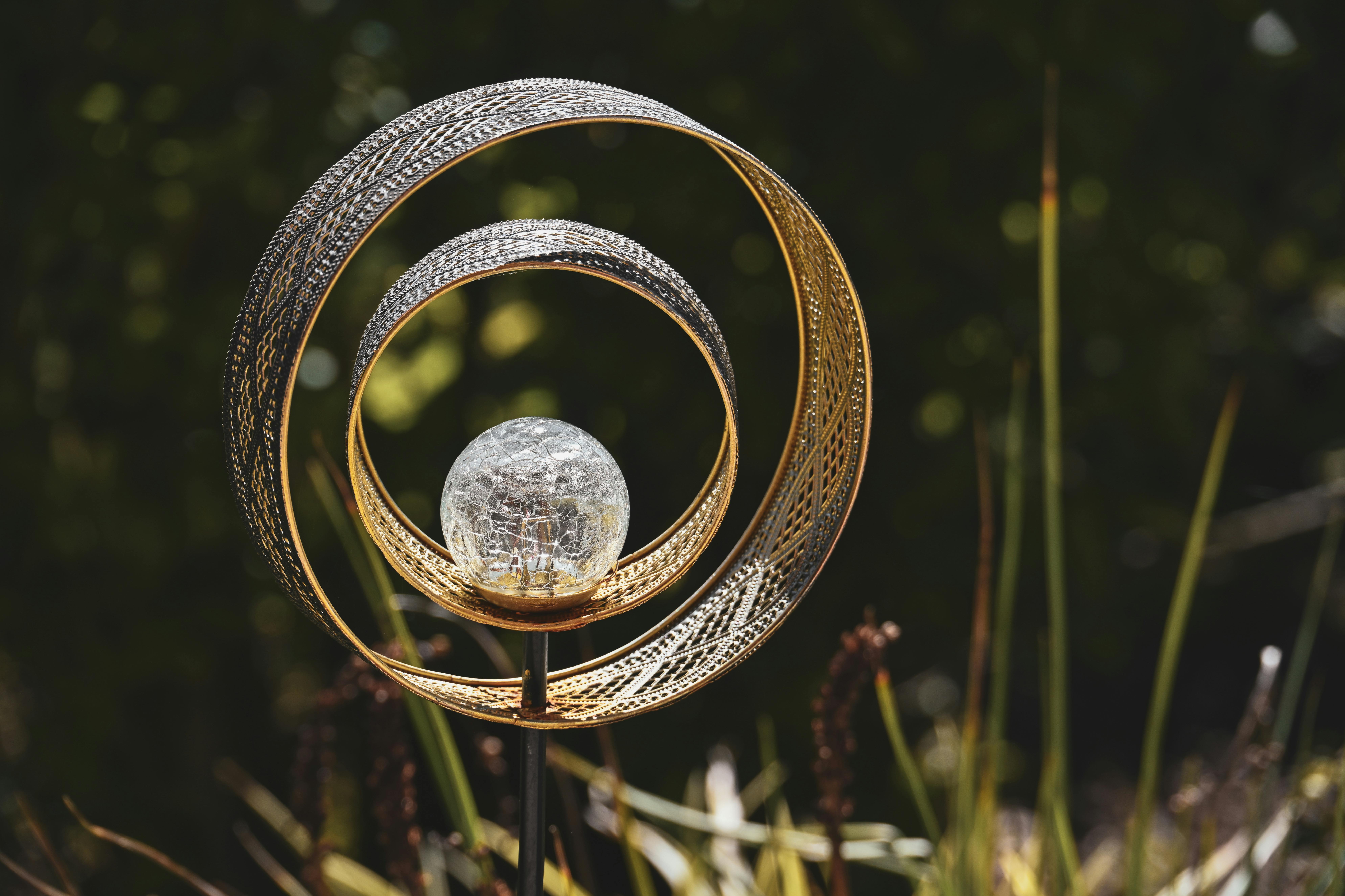 An artistic metal garden sculpture with a decorative glass orb, perfect for outdoor decor.