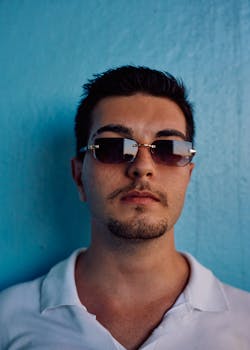 Confident man in sunglasses standing against a bright blue wall in Istanbul, Turkey.