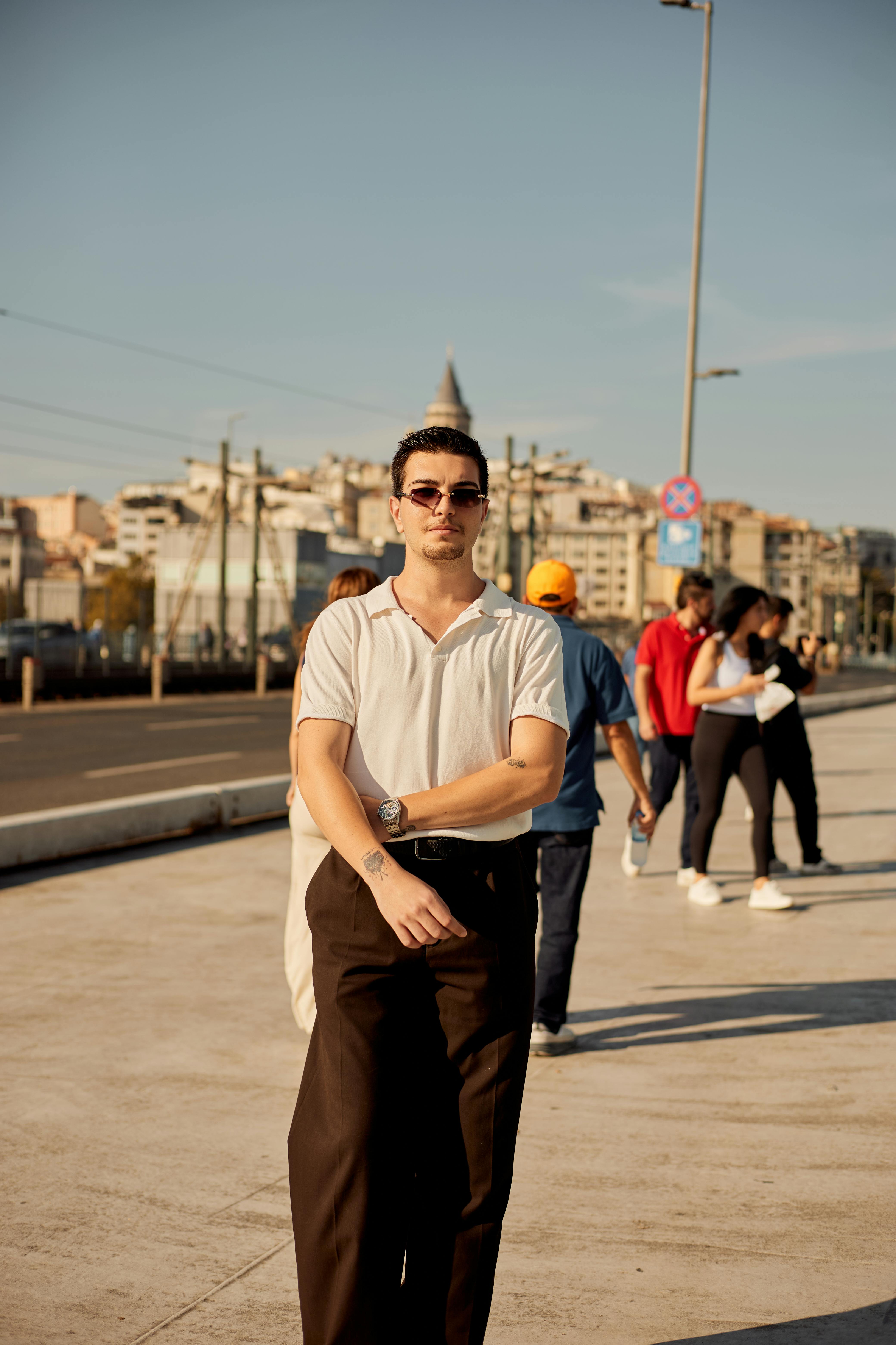 A fashionable man wearing sunglasses walks confidently in Istanbul, capturing a vibrant urban atmosphere.