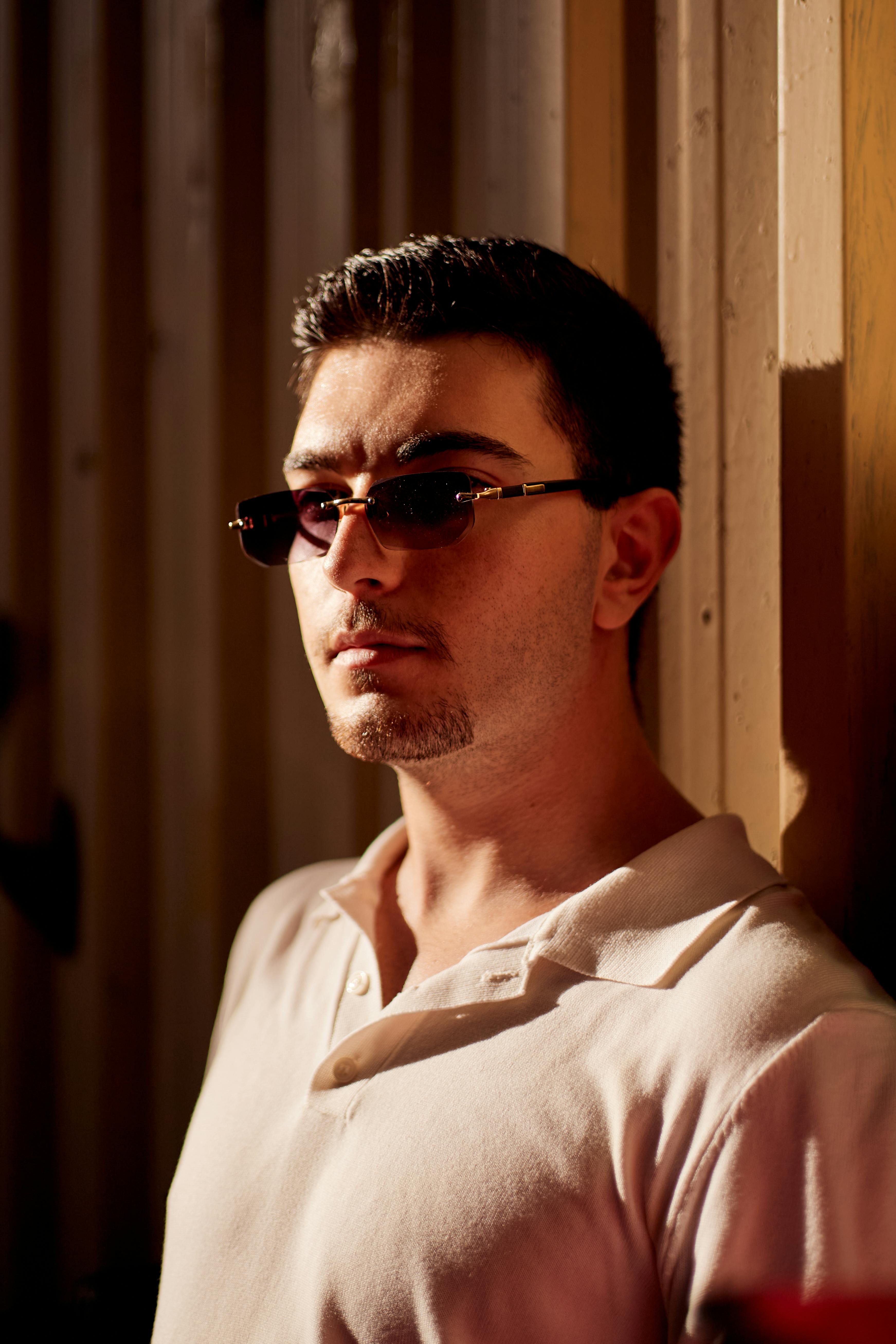 Stylish man wearing sunglasses in a well-lit indoor setting, conveying a modern and confident look.