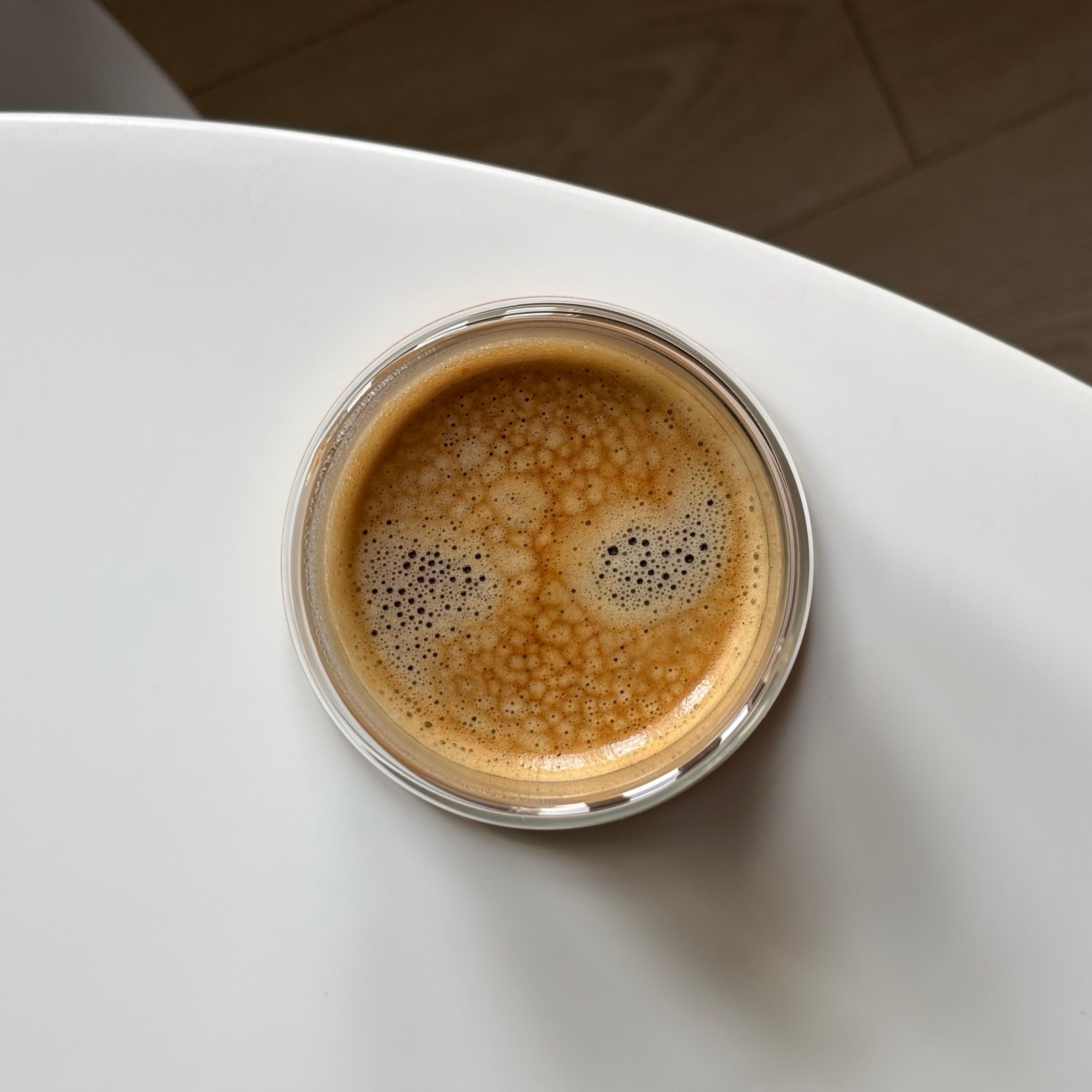 Overhead shot of espresso in a glass on a white table — photo by نشمـيّـه on Pexels