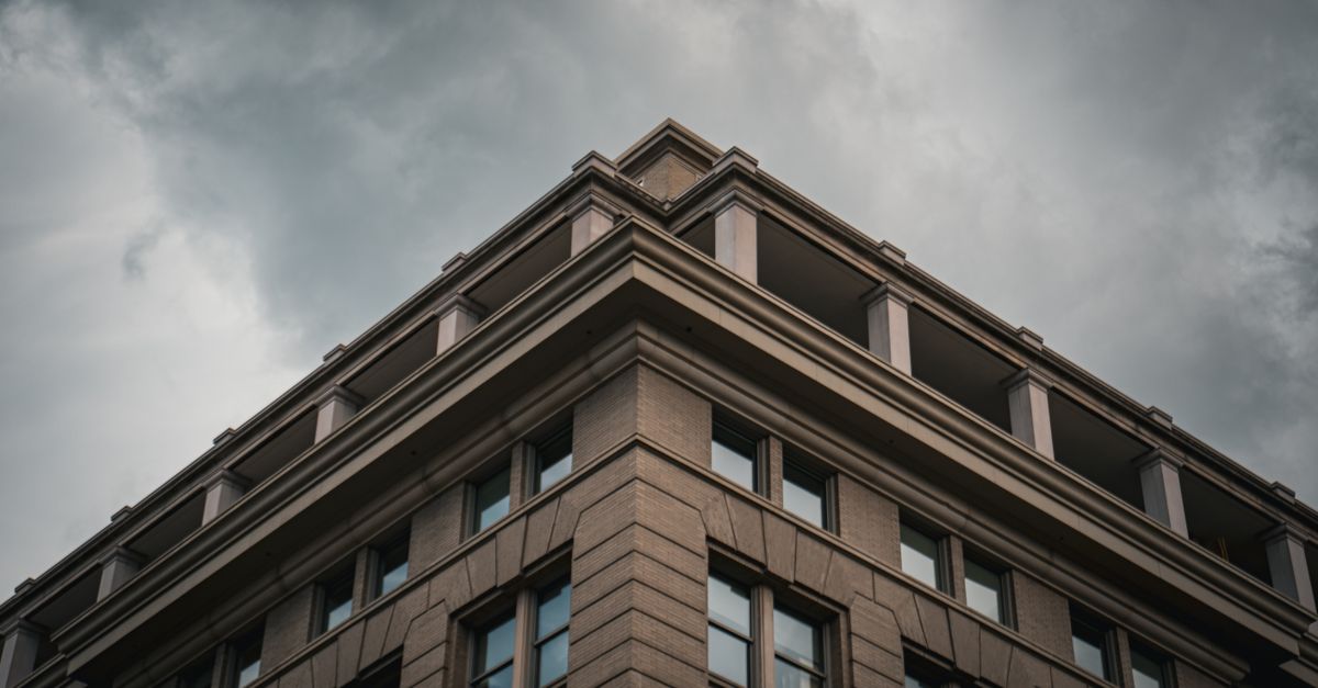 Corner view of a modern urban building with looming clouds.