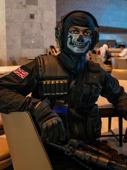 Free Person in tactical gear with skull face paint sitting indoors. Stock Photo