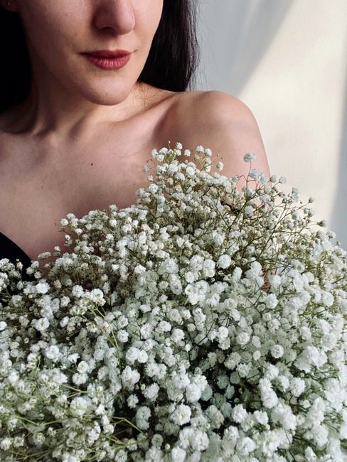 A woman gently holding a bouquet of white baby's breath flowers, bathed in soft, natural light.