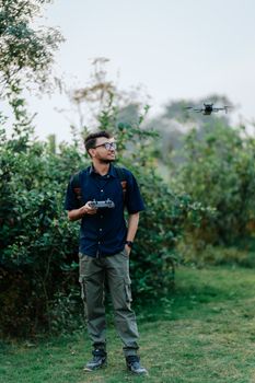 A man operates a drone in a vibrant green outdoor environment.