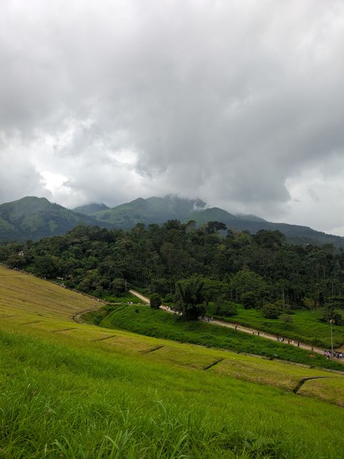 Free A dramatic view of a lush green landscape beneath cloudy skies in a mountainous region. Stock Photo