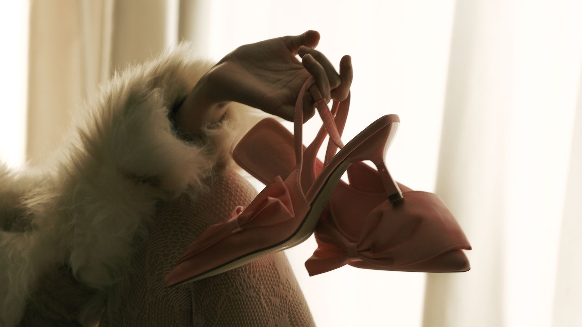 Chic hand with pink high heels against a soft backdrop. Perfect for fashion concepts.