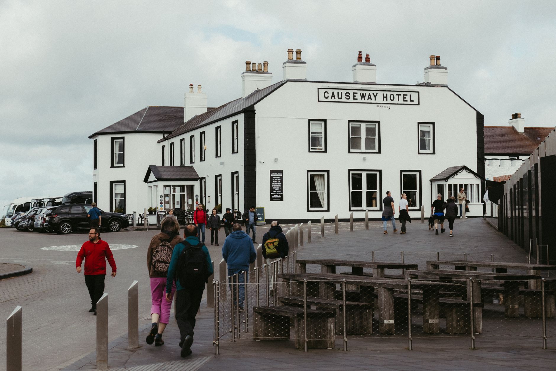 People walking outside the historic Causeway Hotel in Northern Ireland during the day.