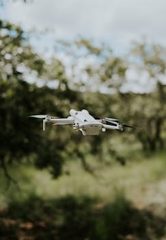 Aerial drone in flight captured in a serene and lush green forest setting on a clear day.