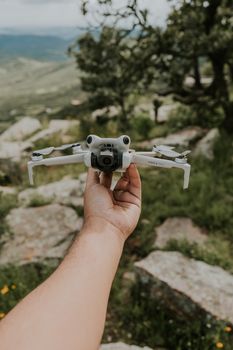 A person holding a drone over a picturesque mountain view, showcasing outdoor adventure and technology.