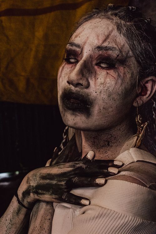 Free Portrait of a woman in gothic attire with striking face paint, captured in a mysterious ambiance. Stock Photo