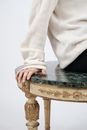 特写镜头：一只手放在一张豪华的绿色大理石与金色相间的桌子上