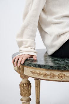 特写镜头：一只手放在一张豪华的绿色大理石与金色相间的桌子上