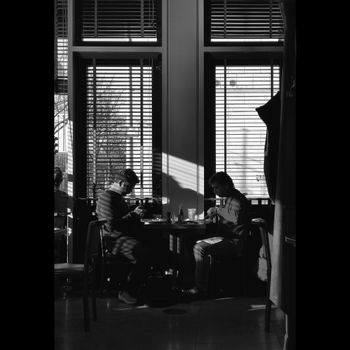 Two adult men dining together in a Berlin cafe, captured in black and white.