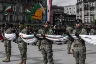 Soldiers in camouflage uniforms hold a flag during a parade in Zócalo, Mexico City.