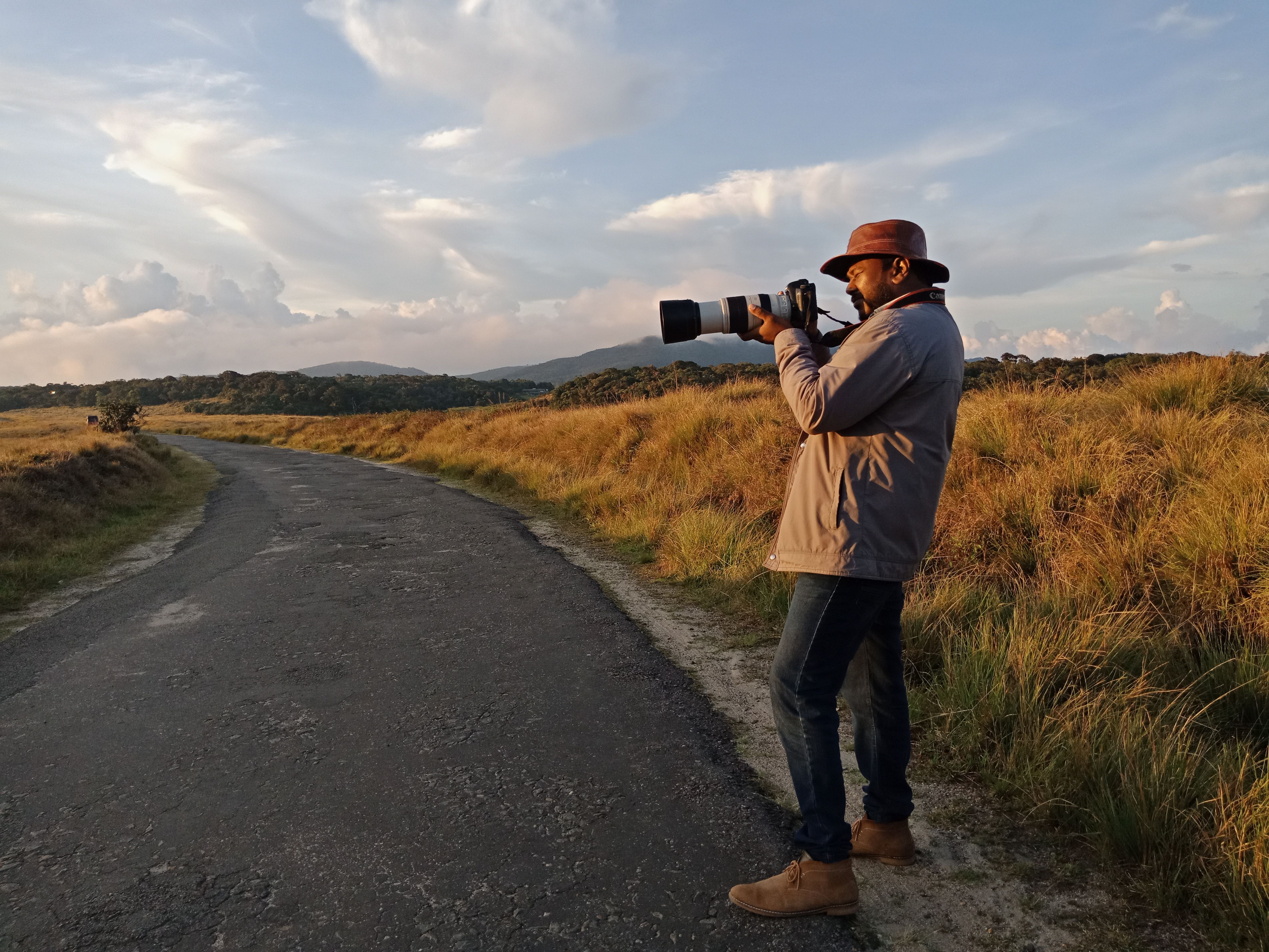 A photographer with a camera capturing a scenic road in Central Province, Sri Lanka.