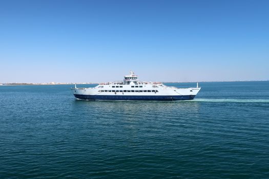 Ferry traversing the calm blue waters under a clear sky in Sfax, Tunisia.